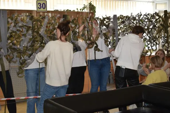 Поки очікують в черзі: у Луцькому ЦНАПі відвідувачі плетуть маскувальні сітки (фото)