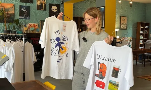 Менеджерка показує брендоваі футболки, які виготовляє соцпідприємство