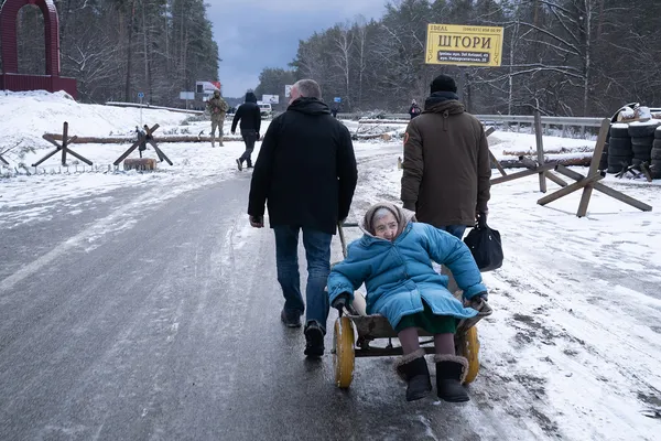 Чоловіки допомагають евакуюватись літний жінці дорогою з Ірпеня