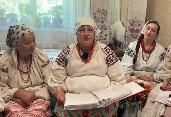 Керівниця колективу показує папку із зібраними за роки піснями