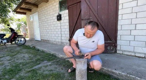 Анатолій Василюк клепає косу перед косінням сіна