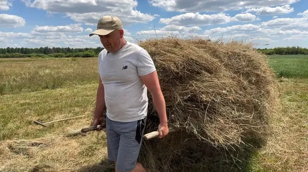 Анатолій Василюк несе сіно носилами