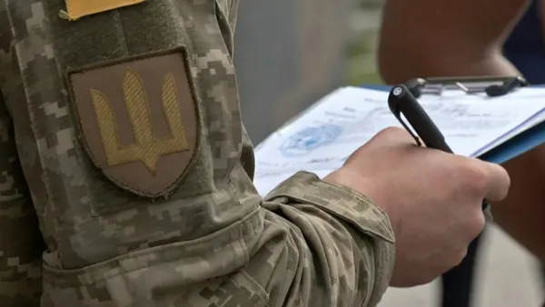 Представник ТЦК у місті Ковелі вписує дані у повістку для військовозобов'язаного, травень 2024 року